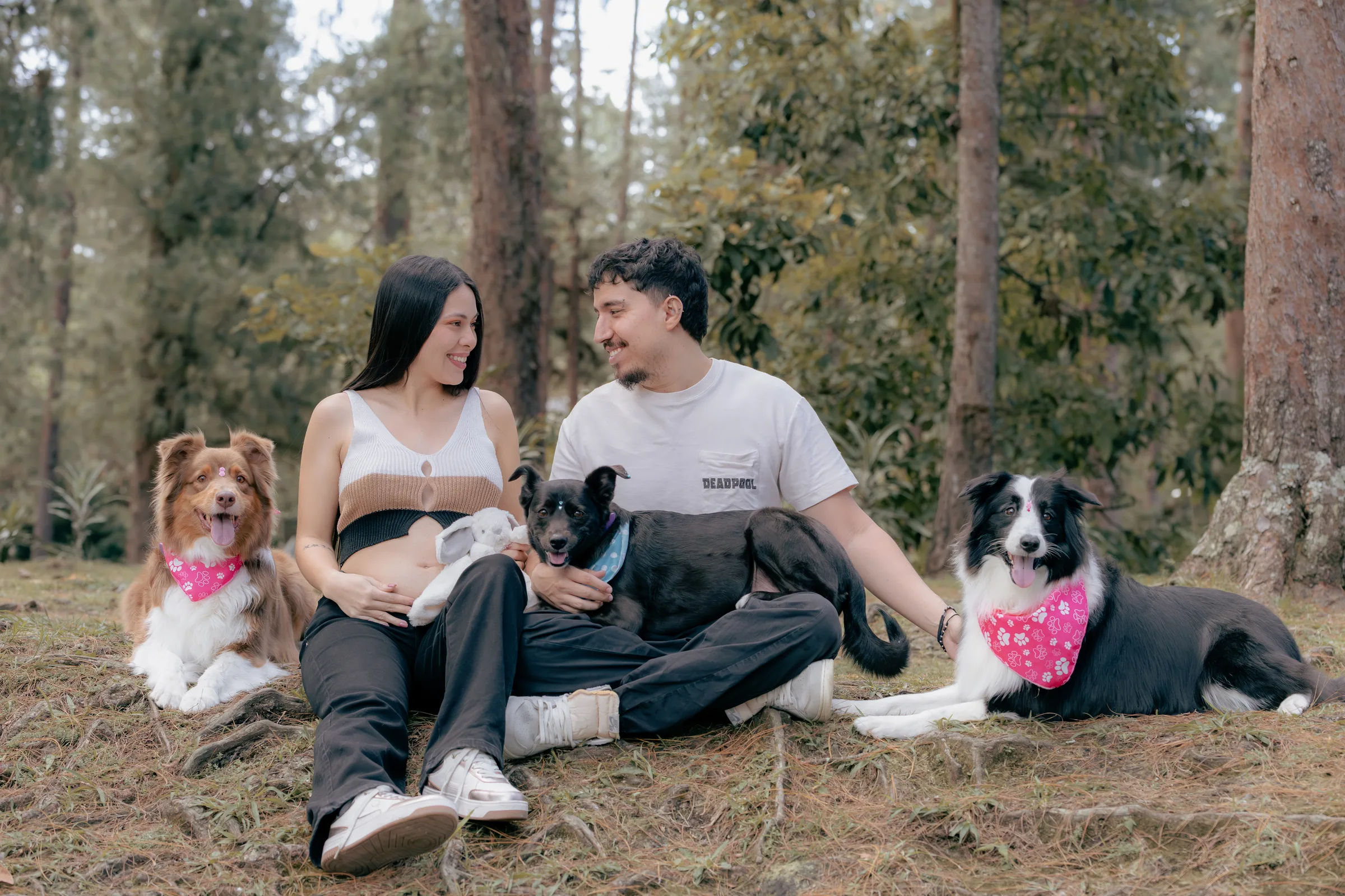 Santiago and Alejandra sitting in a Colombian forest with their three dogs while waiting for Aarón.